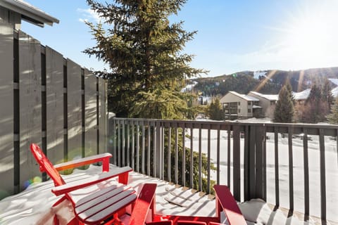 Relax on your private balcony with stunning mountain views, where red Adirondack chairs invite peaceful moments overlooking the snowy alpine landscape.