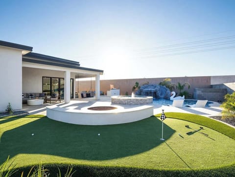 Backyard with large patio, firepit, putting green. Seating area for firepit and putting green.