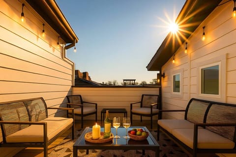 Rooftop terrace at golden hour with outdoor seating, string lights, and refreshments