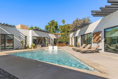Walled pool courtyard w/ lounge chairs, palm views & the home`s glass-wall wing for sunny afternoons.