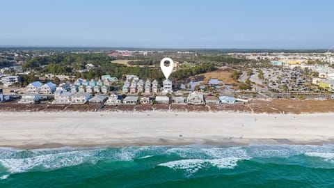 Aerial view of beachfront vacation rental location with pristine white sand beach and turquoise waters just steps away from the property.