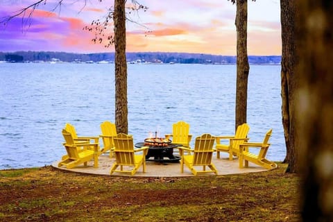 This inviting fire pit area offers a perfect gathering spot surrounded by nature, with Adirondack chairs arranged for enjoying the lake view and cozy fireside evenings.
