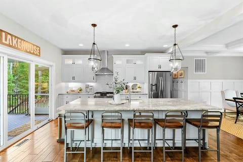 A spacious and modern kitchen with a large marble island, high-end appliances, elegant pendant lighting, and open access to the dining and living areas with views of the backyard.