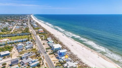 Aerial view of beachfront community with pristine sandy shores and turquoise waters stretching along the coast.