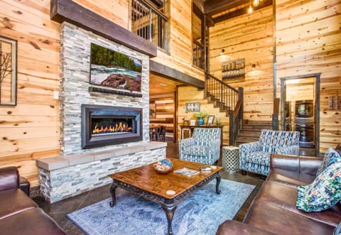 The living room beckons with its towering stone fireplace, cozy seating, and wood-paneled walls—perfect for unwinding after a day of exploring.