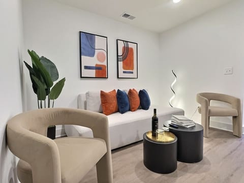 This living room exudes contemporary charm with its clean lines and minimalist design, creating a serene atmosphere perfect for relaxation or entertaining.