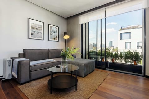 Living room with modern L-shaped sofa, coffee table, and large windows opening to the balcony.