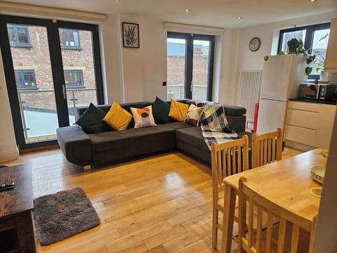 Spacious and sunny living area with a cozy corner sofa, dining table, and balcony — ideal for family meals and movie nights. TV, Sofabed, Dinning table, Balcony, Netflix, Ready to cook kitchen, Wine glasses, Games and Books