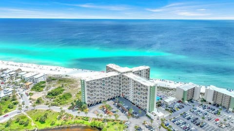 Beachfront resort complex featuring pristine white sand and emerald waters just steps from multiple property buildings.