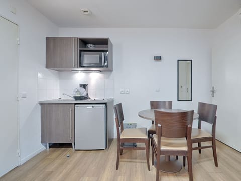 Fully equipped kitchenette with modern appliances and a dining table for two, blending convenience and style.