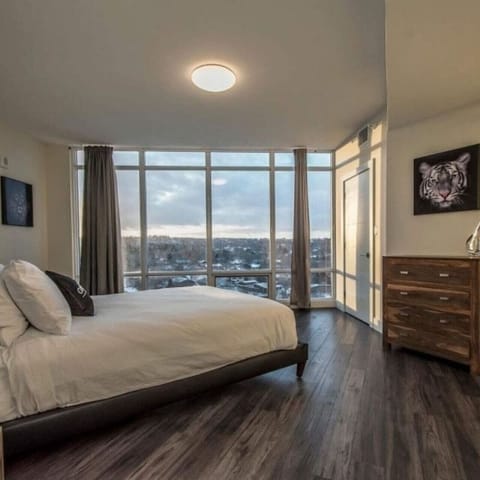Wake up to stunning natural light and peaceful views from a plush queen-size bed, complete with ample wooden dresser storage, blackout drapes, and direct balcony access.