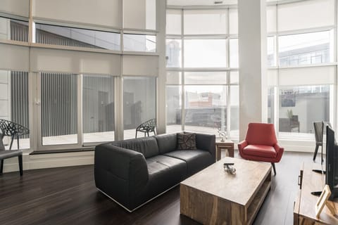 A sanctuary in the sky. Sink into the supple leather sofa and enjoy a stunning panorama from dramatic, double-height windows that bathe the entire open-plan space in bright, natural light, all with direct access to your private balcony for true indoor-out