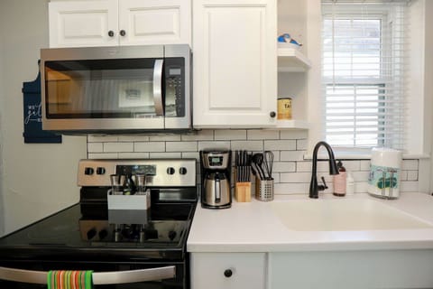 Kitchen with stove, oven, coffee maker, utensils, storage space, micrwave, a window and soap.