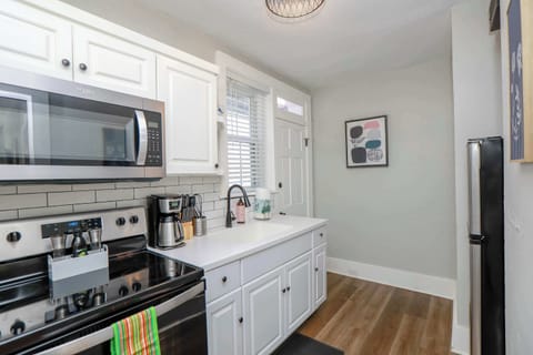Kitchen with an oven, stove, coffee maker, refrigerator, micrwaove, additional storage, and utensils.
