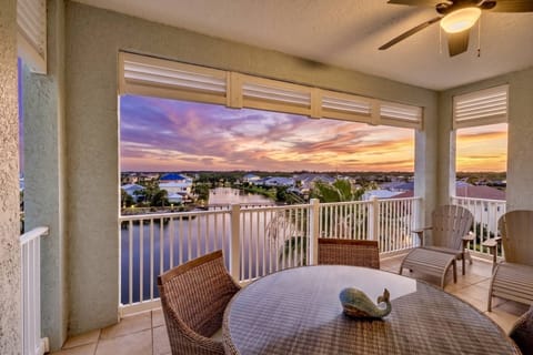 Cinnamon Beach balcony lake view near the ocean with a beautiful sunset sky in orange, pink, and purple tones reflecting over calm water.