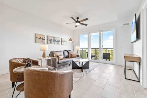 Modern living room with leather seating and balcony access offering scenic views.