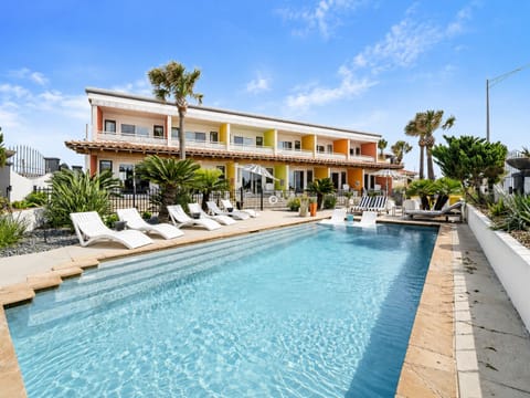 Beachfront resort-style swimming pool with luxury lounge chairs, palm trees, and direct Gulf Coast views at this Galveston vacation rental on Seawall Boulevard.