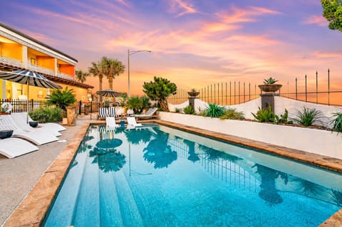 Oceanfront Galveston condo pool at sunset with lounge chairs, tropical landscaping, and relaxing coastal resort views.