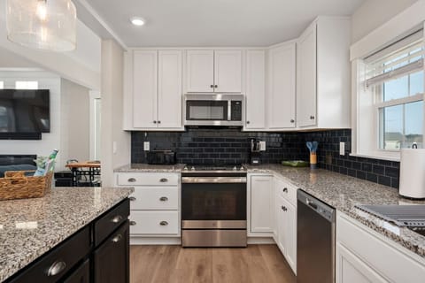 Bright kitchen w/ white cabinetry, granite counters, & plenty of space to cook together