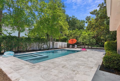 Your private backyard oasis awaits: dive into the sparkling pool, relax under the vibrant umbrella, and soak up sunshine surrounded by lush greenery and serene privacy.
