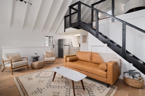 Open main floor living area — vaulted ceilings, leather sofa, spiral staircase leading to the loft king