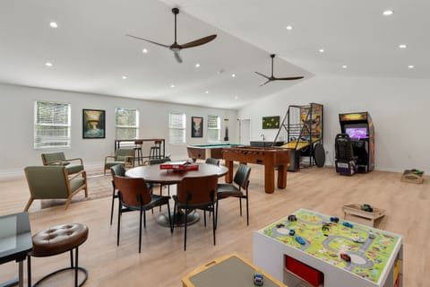 Shared game room at Notestone Reserve (separate building) — pool table, arcade machines, foosball, and 85" Smart TV, open to all guests