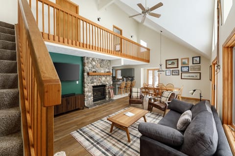 Bright living area w/ lofted ceiling, fireplace & open railing above creates an airy, welcoming retreat.