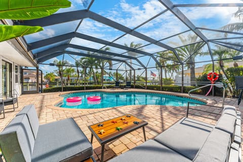 Enjoy a screened pool with lounge chairs, pink floats, and tropical vibes.
