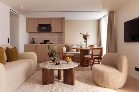Une belle pièce à vivre dotée d'un canapé convertible, une table d'appoint, une table à manger et une TV.  Cuisine ouverte sur la pièce à vivre