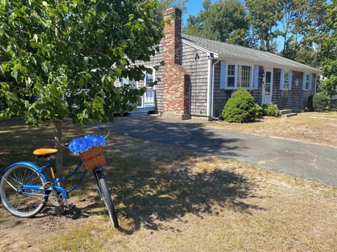 This inviting 3-bedroom beach cottage captures the true Cape Cod feel with cedar-shingled siding, light blue shutters, and a welcoming front entrance.