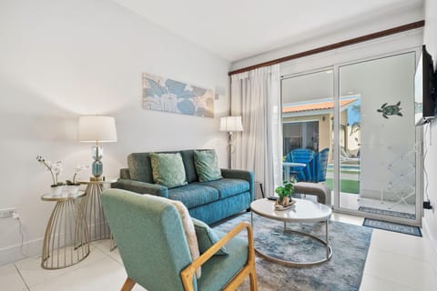 Stylish living area with a plush sofa & vibrant decor for a relaxing atmosphere - Large sliding glass doors fill the space with natural light & lead to outdoor patio - Perfect spot to unwind, watch TV or enjoy a morning coffee with a beautiful view