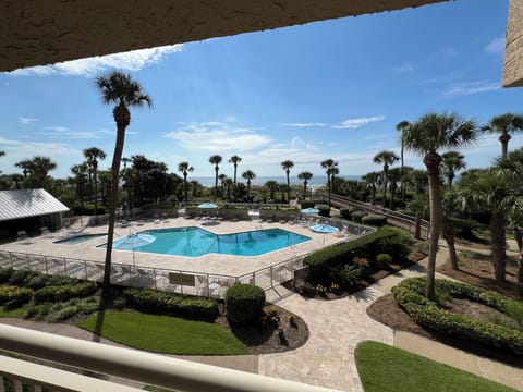 View of pool from balcony w/ beach in background