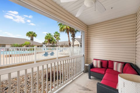 Unwind on your private balcony with plush seating and tropical palm views beyond the pool area.