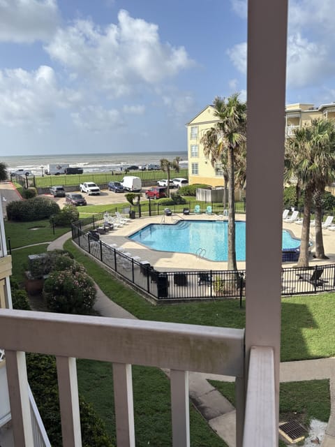 Balcony view of the pool, palm trees, and beach just beyond