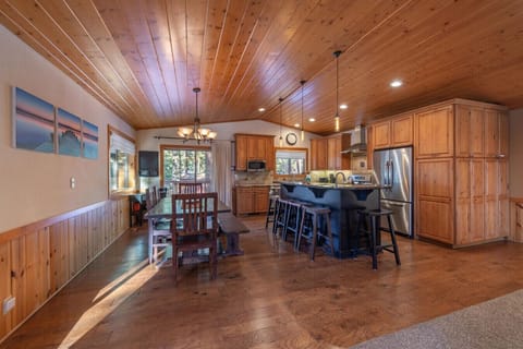 Large open great room (living room, dining area, kitchen) with river rock fireplace, beautiful furnishings, and 60 inch SmartTV.