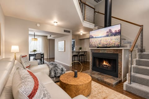 From the living room, enjoy a clear view of the stairs leading to the loft space, complemented by a cozy fireplace and a large smart TV, creating a perfect blend of comfort and style.