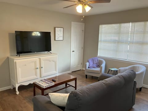 Bright and cozy living room with a smart TV, plush couch, and inviting decor, perfect for relaxing after exploring Stephenville