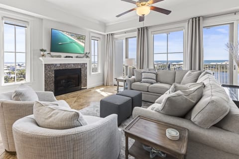 Unwind in your elegant living room with plush seating, cozy fireplace, and stunning ocean views through floor-to-ceiling windows.