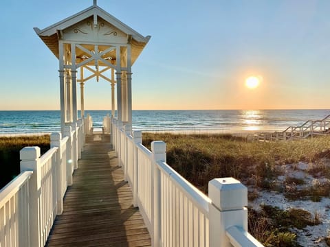 A picturesque sunset gazebo overlooks the beach, framing stunning ocean views and warm golden light over the water—a scenic arrival feature near the property.