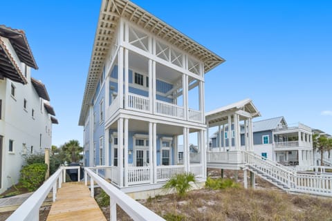 A charming coastal cottage with classic white railings and covered porches where beach memories are made.
