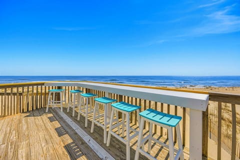 Oceanfront deck with bar seating showcasing endless sea views and sandy beach access for your coastal getaway.