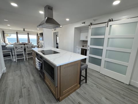 Kitchen view of island with flat top stove, built in range and microwave