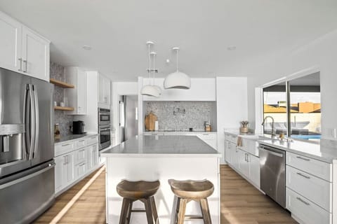 Sleek white kitchen with stainless steel appliances and generous counter space.