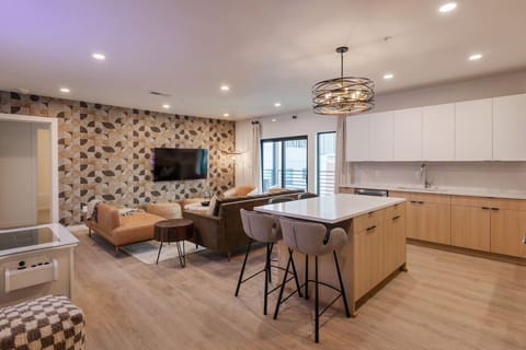Open-concept living space with modern kitchen, stylish patterned accent wall, and comfortable seating area.