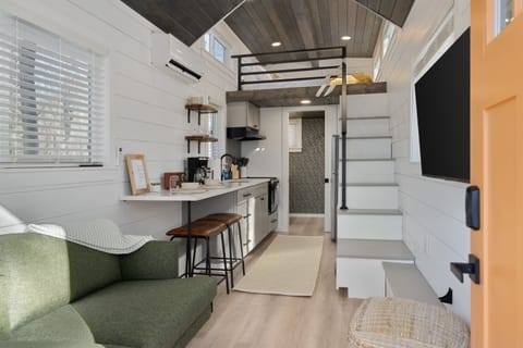 Main floor living area at Whitman — kitchenette, living space, and staircase to the lofted queen bed above