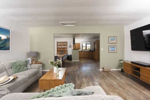 Living area with corner sofa and chairs seating eight, 46 inch Smart TV with Sky package. Patio doors with distant sea views