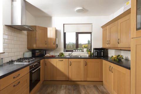 Kitchen with electric oven and hob, dishwasher, microwave, fridge/freezer, kettle, toaster and a range of pans and utensils.
