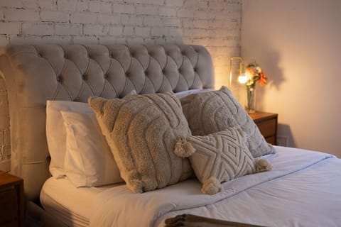 bedroom 1: Cozy bedroom with tufted headboard and layered pillows for ultimate comfort.
