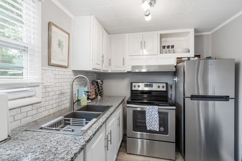 Enjoy a fully stocked kitchen featuring a sleek stainless steel fridge, oven, and range hood, plus plenty of counter space for cooking meals