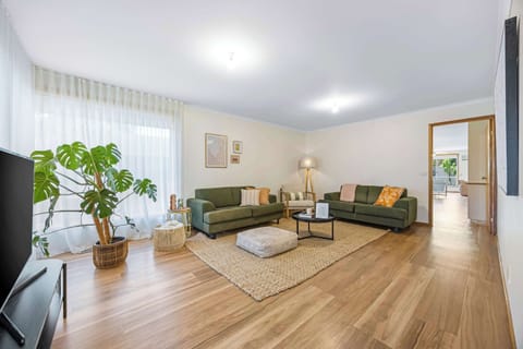 Separate living room with TV, natural light, beautiful flooring and ample seating.